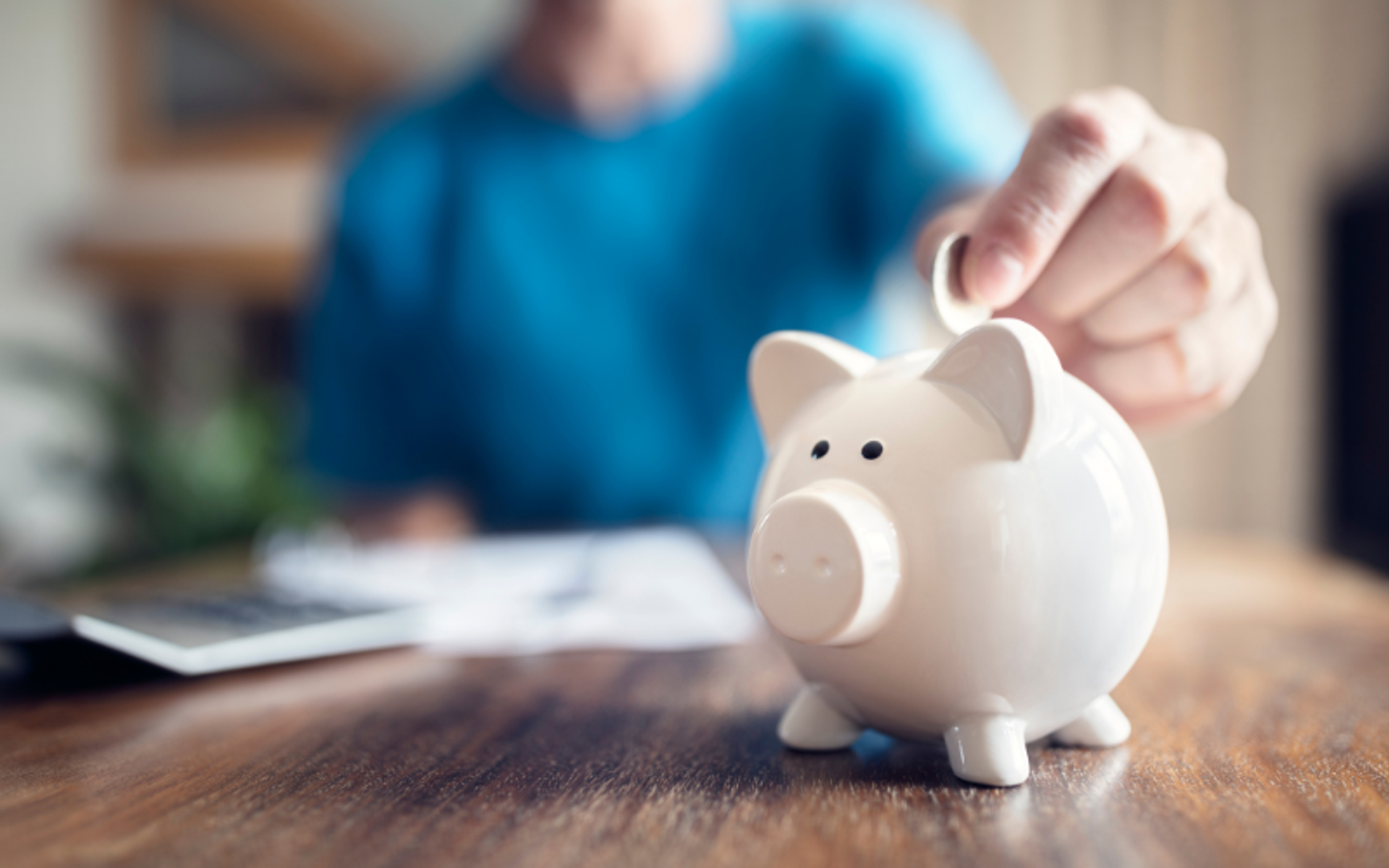 Person putting money in a piggy bank